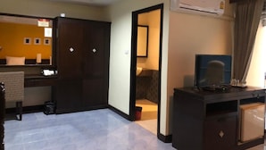 A hotel room with a large wardrobe, a desk with a computer, an air conditioning unit, and a bathroom visible through an open door. - J Hotel (Krabi)