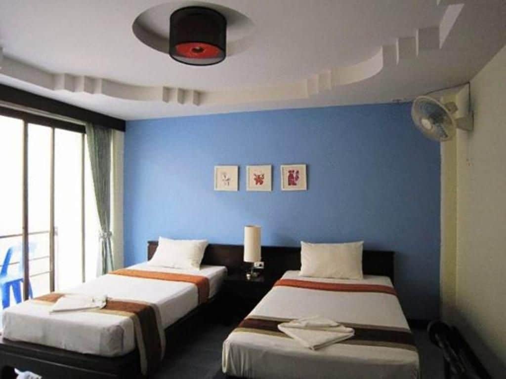 A hotel room with two beds, a ceiling fan, and a window with curtains.