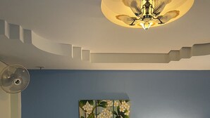 A hotel room with a bed, a nightstand with a lamp, a wall-mounted painting, and a ceiling fan. - J Hotel (Krabi)