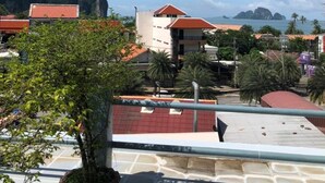 A coastal view with buildings, a clear sky, and a potted plant in the foreground. - J Hotel (Krabi)