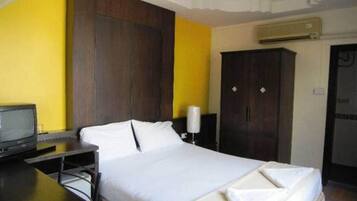 A hotel room with a bed, a desk, a television, and a wardrobe.
