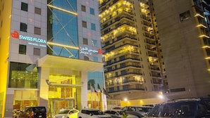 A hotel with a modern facade, multiple balconies, and a prominent sign for the Swiss Flora Inn Hotel in Riyadh. - Swiss Flora Inn Hotel Riyadh (Riyadh)