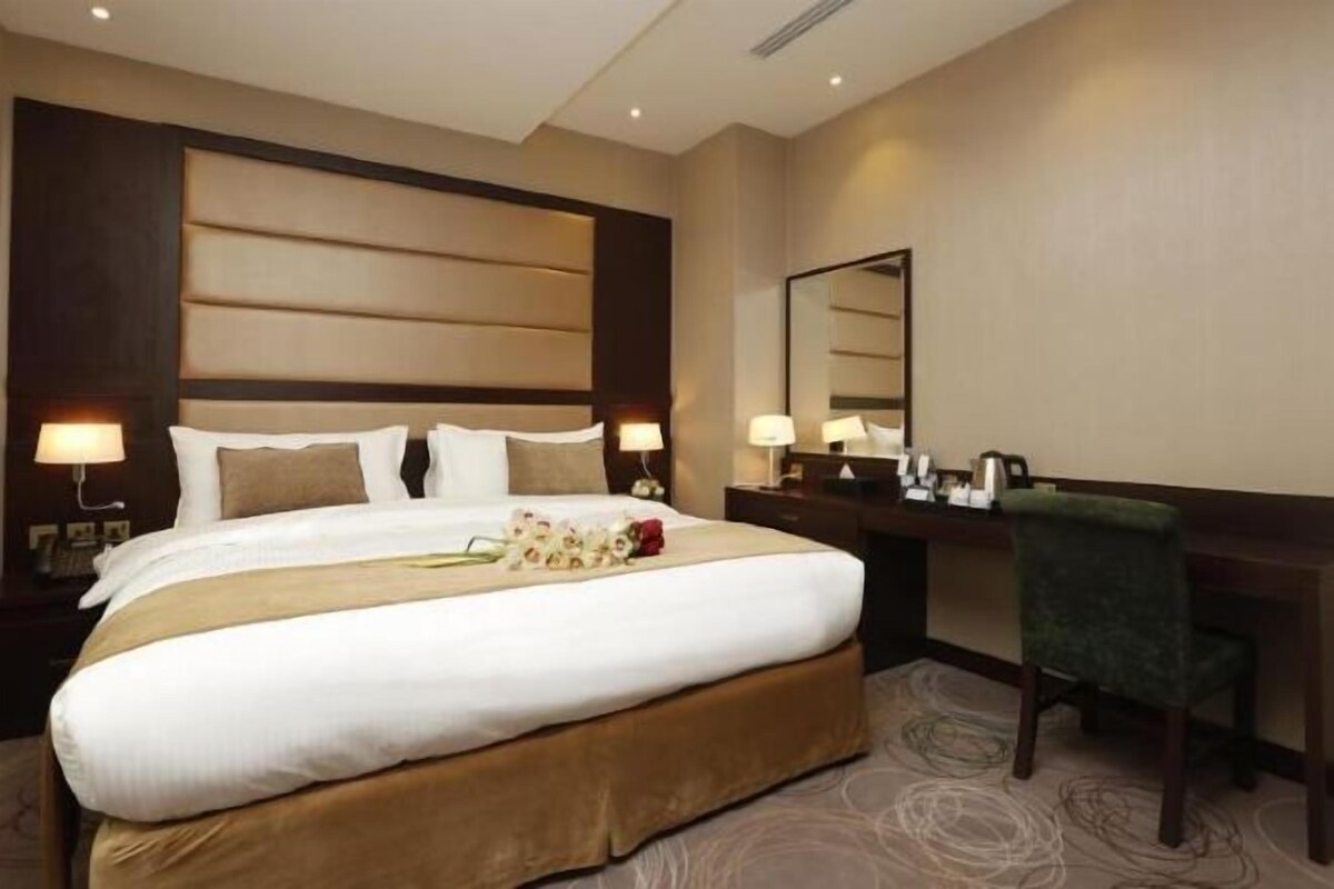Ein Hotelzimmer mit einem großen Bett, Nachttischen inklusive Lampen, einem Schreibtisch und einem Sessel.