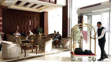 A lobby with seating, a reception area, and a luggage cart.