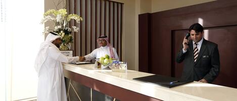 A hotel reception desk with a reception desk, a clock, and a vase of flowers.