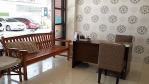 A reception area with a wooden bench, a reception desk, and a patterned wall. - Island Mansion (Krabi)