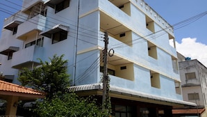 A multi-story building with balconies, a visible power line, and a tree in the foreground. - Island Mansion (Krabi)
