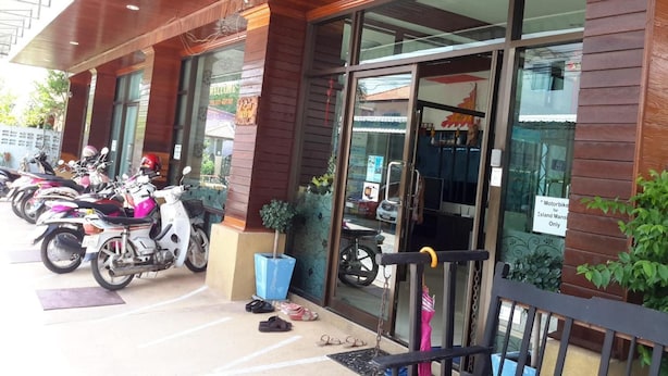 A building with a wooden facade, large glass windows, and a row of parked motorcycles outside. - Island Mansion (Krabi)