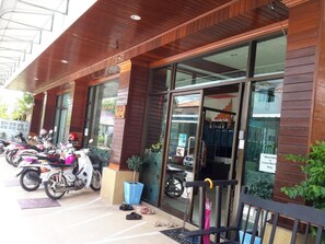 A building with a wooden facade, large glass windows, and a row of parked motorcycles outside. - Island Mansion (Krabi)
