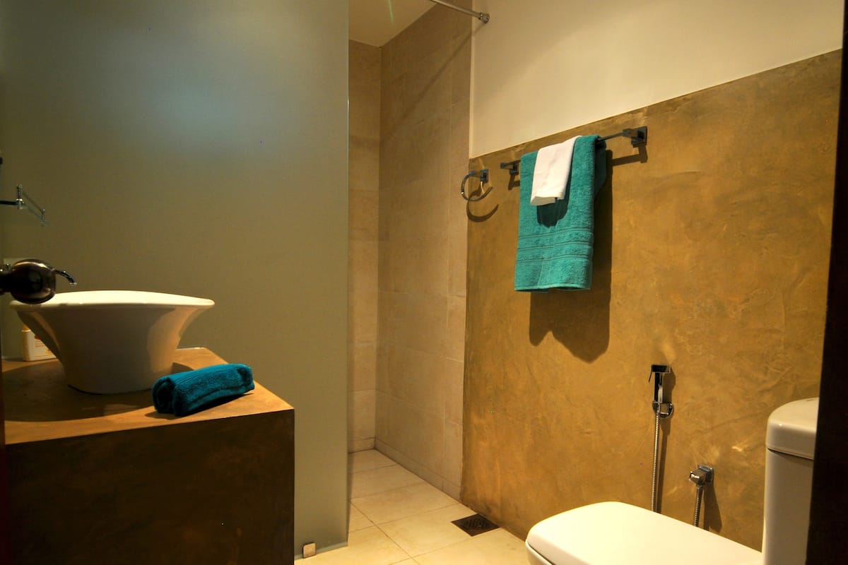 Une salle de bain moderne avec un lavabo blanc, une douche équipée d’un porte-serviettes et des toilettes.
