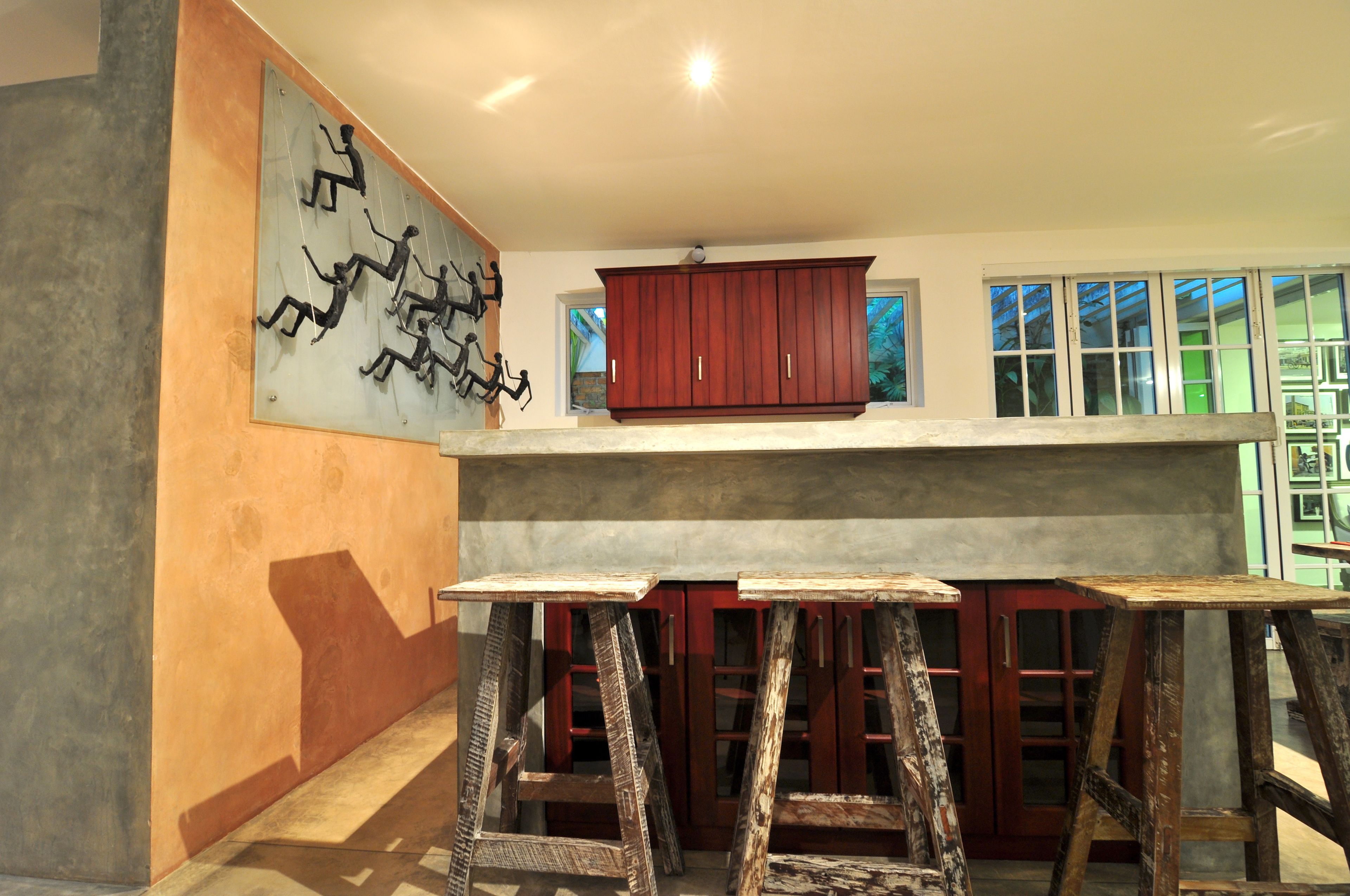 A kitchen with a high ceiling, a wooden cabinet, and a painting on the wall.