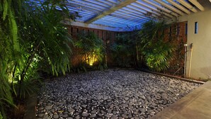 Un jardin intérieur avec un chemin de gravier, différentes plantes et un mur de briques.