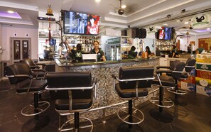 Un espace bar doté de plusieurs tabourets, d’un comptoir et d’un écran de télévision diffusant un événement sportif.