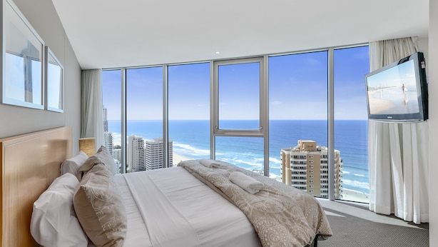 Una habitación de hotel con una cama grande, televisión y vista al océano.