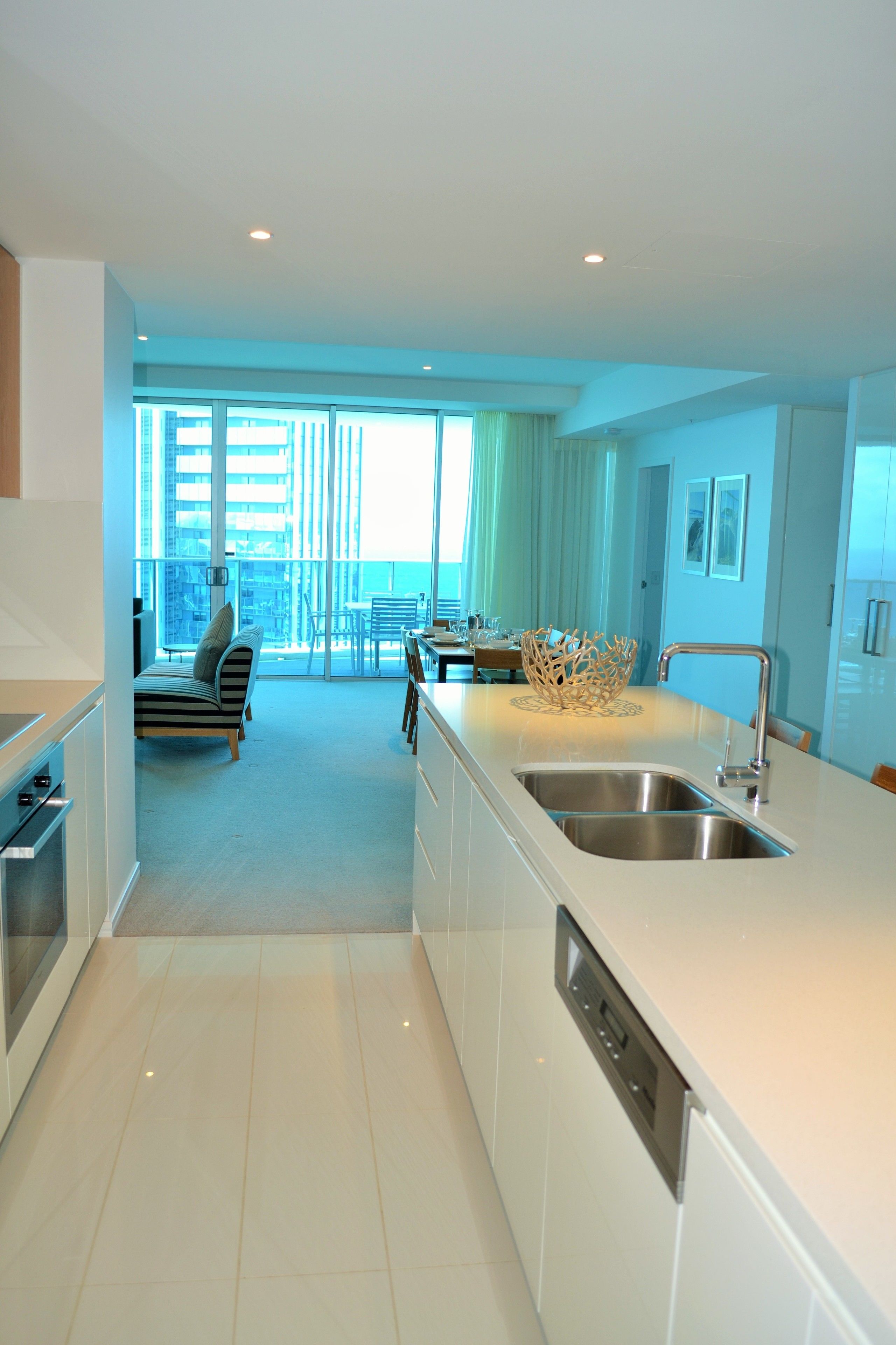 A modern kitchen with a large island, stainless steel appliances, and a view to a balcony.