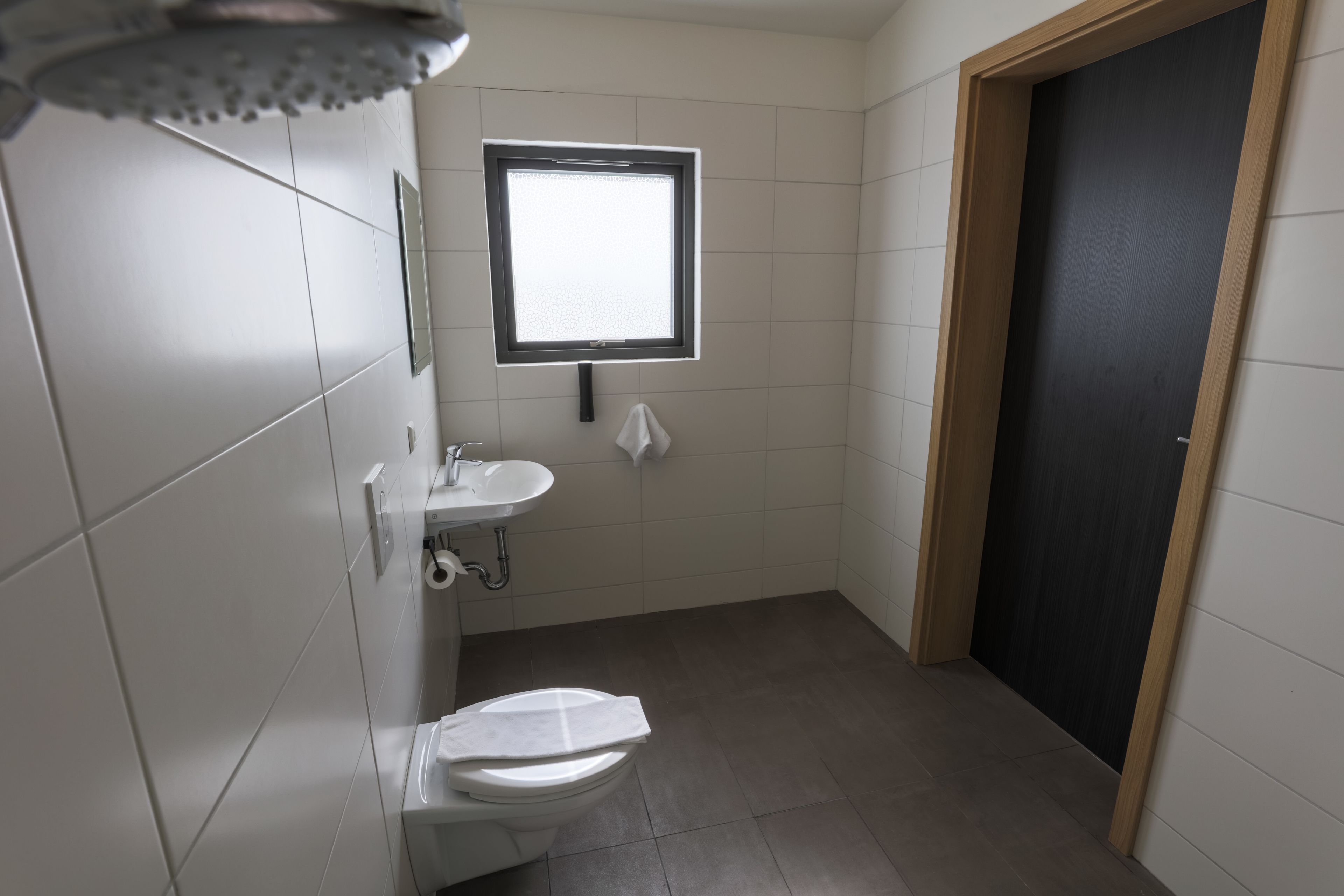 A small, modern bathroom with a toilet, sink, and window.