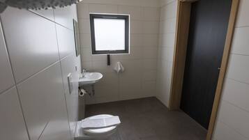 A small, modern bathroom with a toilet, sink, and window.