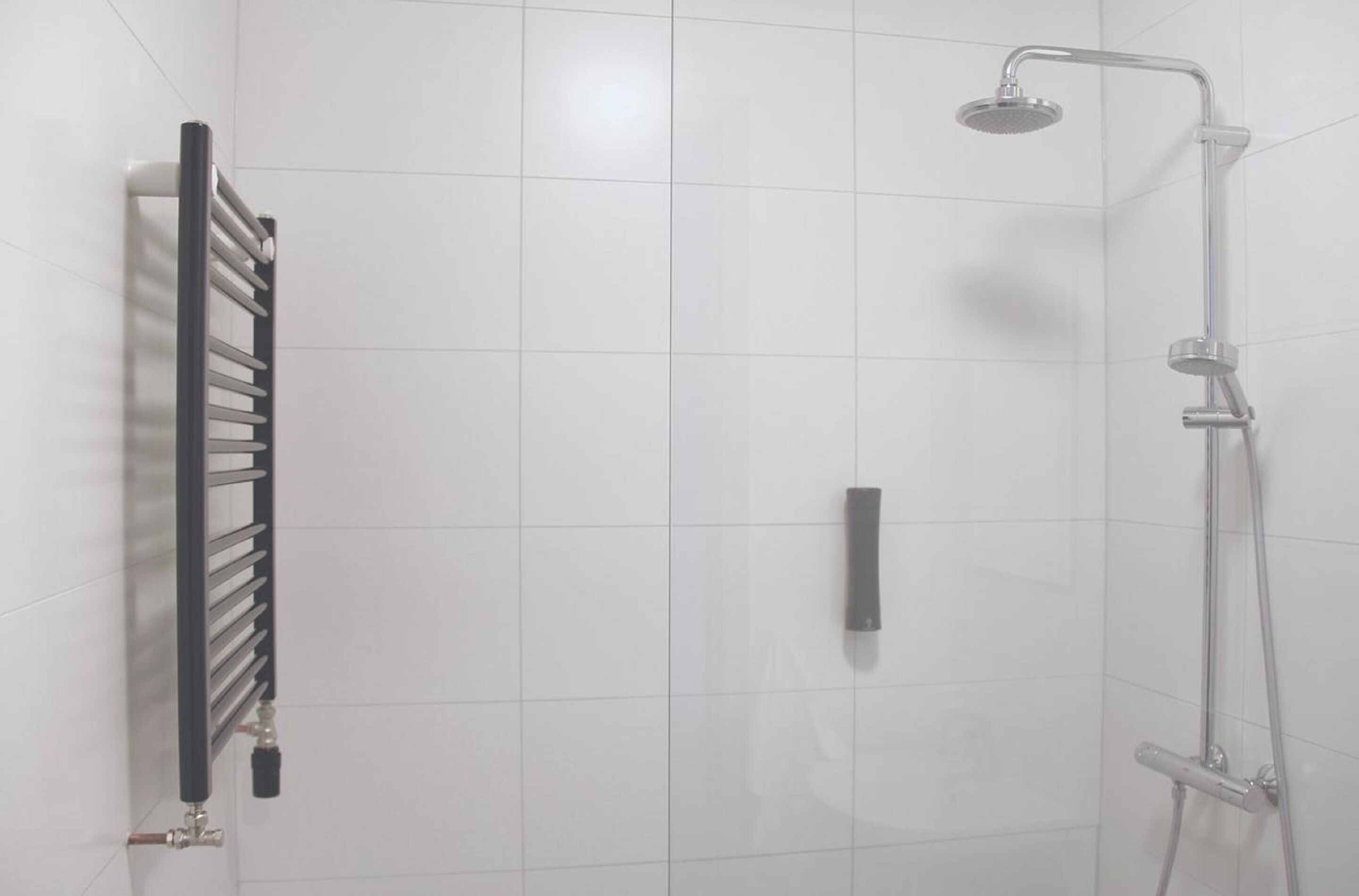 A bathroom with a shower, a towel rack, and a toilet.