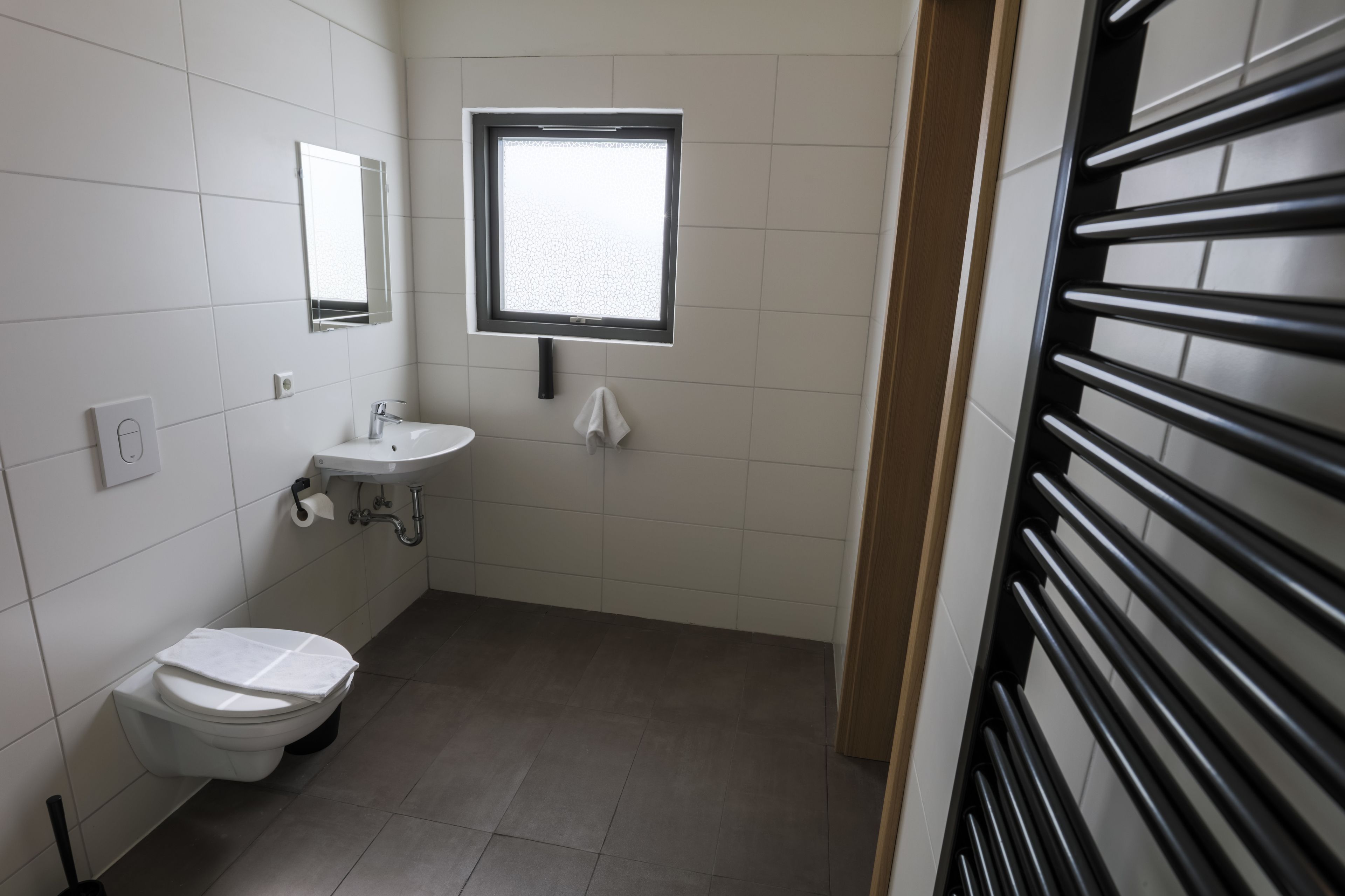 A small, clean bathroom with a toilet, sink, and mirror.