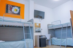 Una camera del dormitorio con letti a castello, una scrivania, una sedia, una televisione e un quadro appeso al muro.