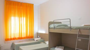 Una habitación con literas, una ventana con cortinas naranjas y una pared blanca.