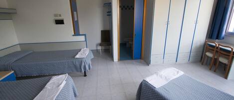 A hotel room with two single beds, a wardrobe, a chair, and a bathroom visible through an open door.