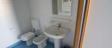 Un baño con inodoro, bidé y lavamanos.