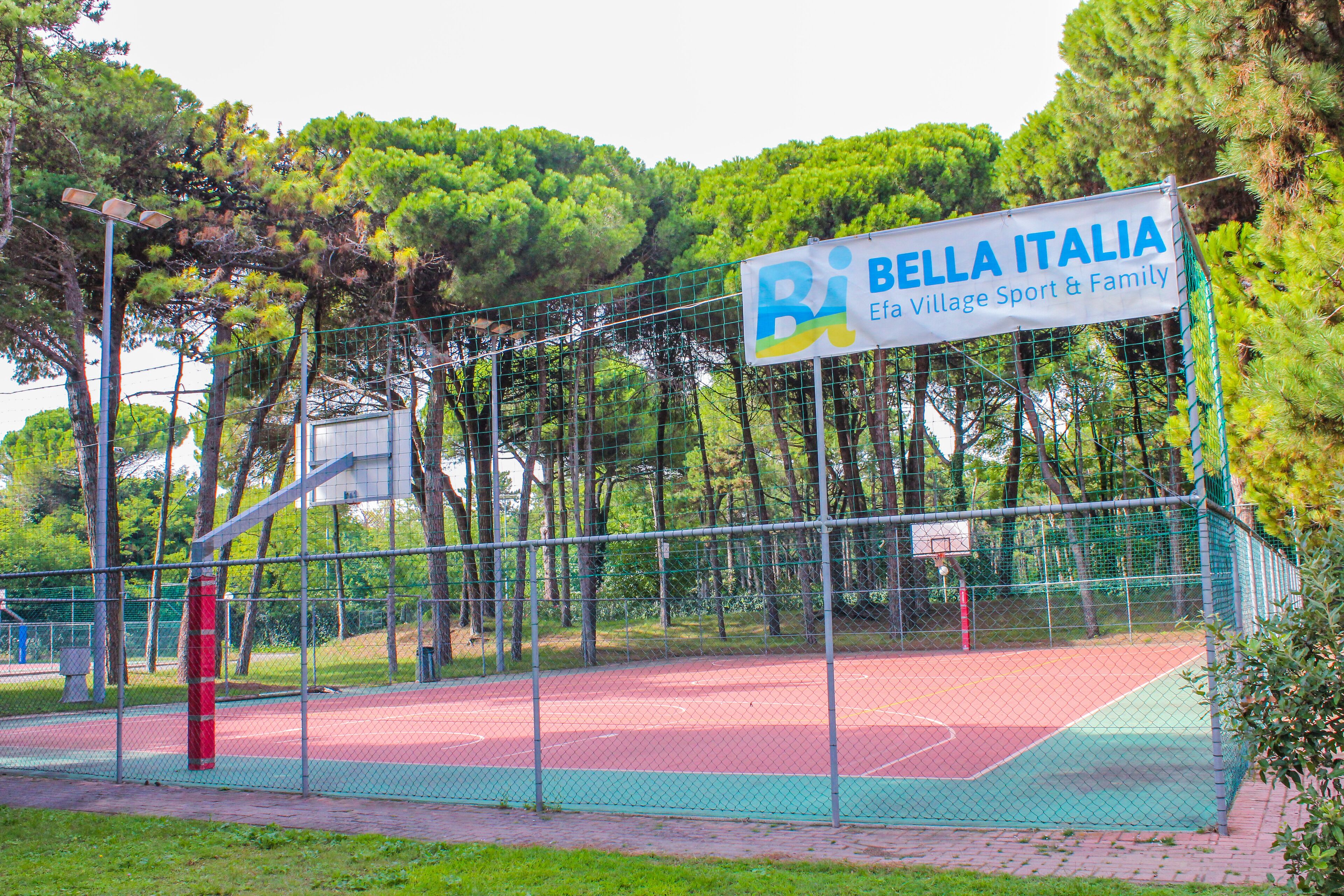Una cancha de baloncesto con un cartel que dice 'Bella Italia Efa Village Sport & Family'.