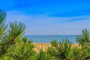 Une plage avec un drapeau, des chaises de plage et des parasols.