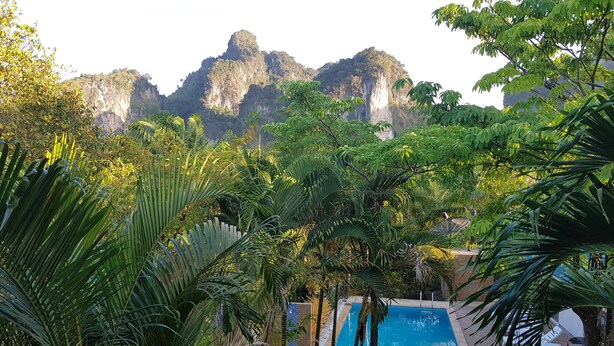 A pool area with white lounge chairs and a view of a mountainous landscape. - Real Relax Resort & Beauty Massage (Krabi)