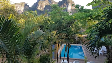 A pool area with white lounge chairs and a view of a mountainous landscape.