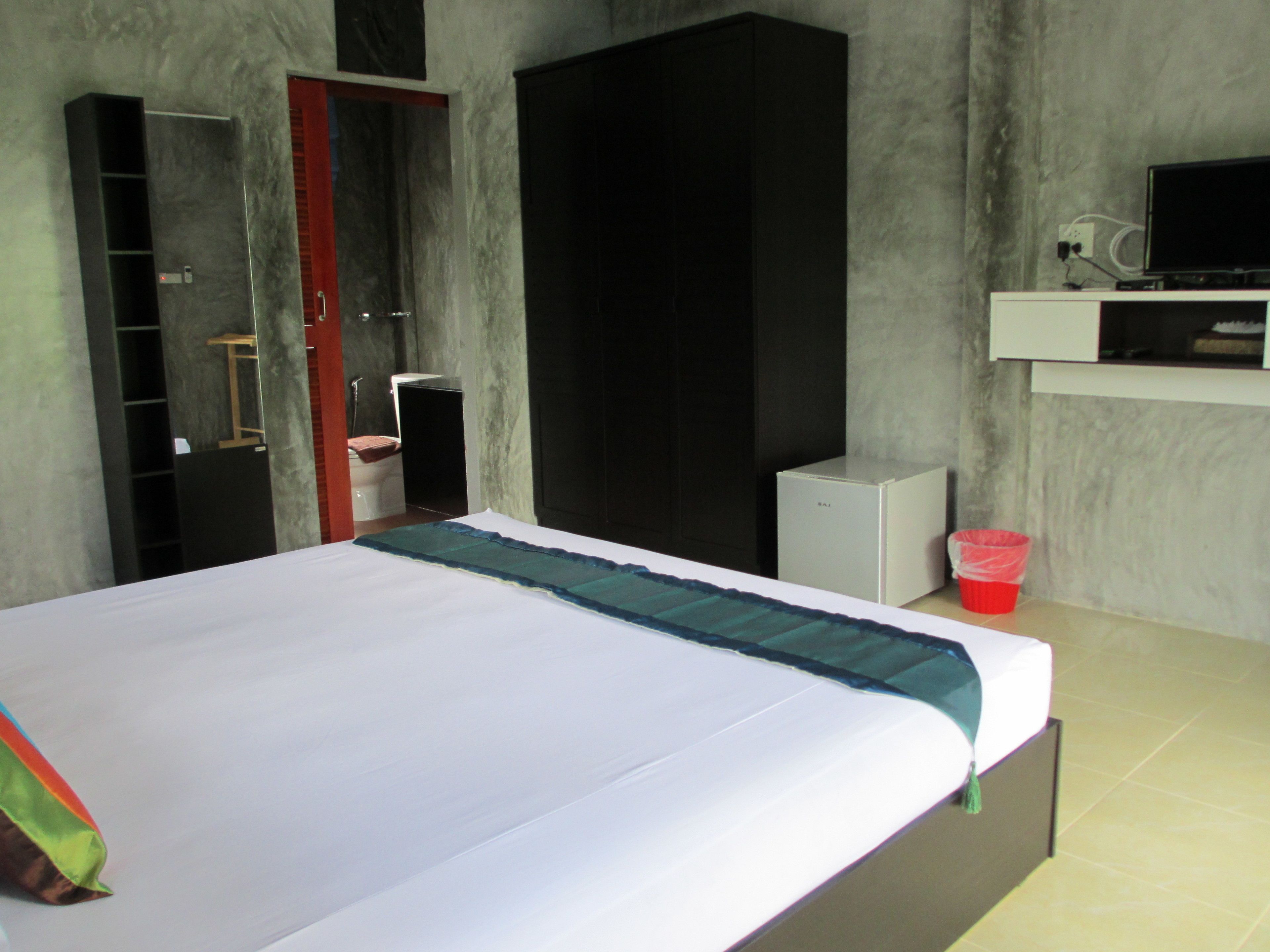 A bedroom with a bed, a wardrobe, a television, and a small cabinet.