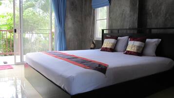 A large bed with a white and red bedspread, a dark headboard, and two pillows with gold and white patterns.