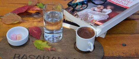 Una mesa de madera con un vaso de agua, una taza de café, un libro y un par de gafas.