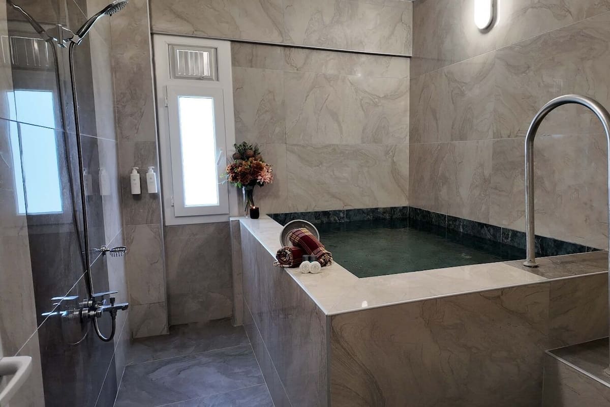 A modern bathroom with a freestanding bathtub, a shower area, and a window with a view.