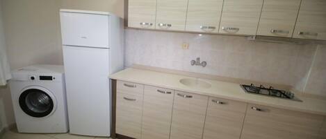A compact kitchen with a washing machine, a sink, and cabinets.