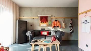 A modern living space with a sofa, a table, a refrigerator, and a mirror.