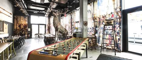 A foosball table in a modern indoor setting with a large window and a mural of a deer.