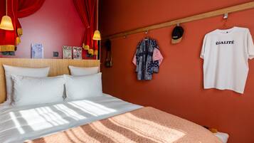 A neatly made bed with white linens, a red wall, and a wooden headboard.
