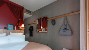A hotel room with a large bed, a smaller bed, a mirror, a hanging bag, and a stuffed toy.
