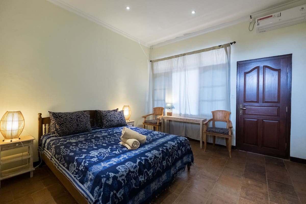 A bedroom with a large bed, bedside lamps, a desk, and a chair.
