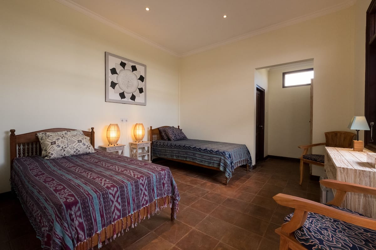 A room with two beds, a wooden table, and a chair.