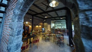 A restaurant with brick walls, wooden tables, and a modern kitchen in the background. - Easy Surf Camp (Kuta)