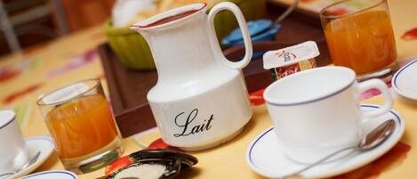 A breakfast setting with a pitcher labeled "Lait," a cup and saucer, a glass of orange juice, and a bowl of food.