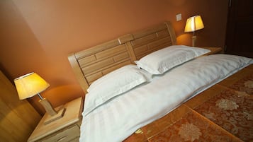 Una cama doble con sábanas blancas, un cabecero de madera y dos lámparas de noche.