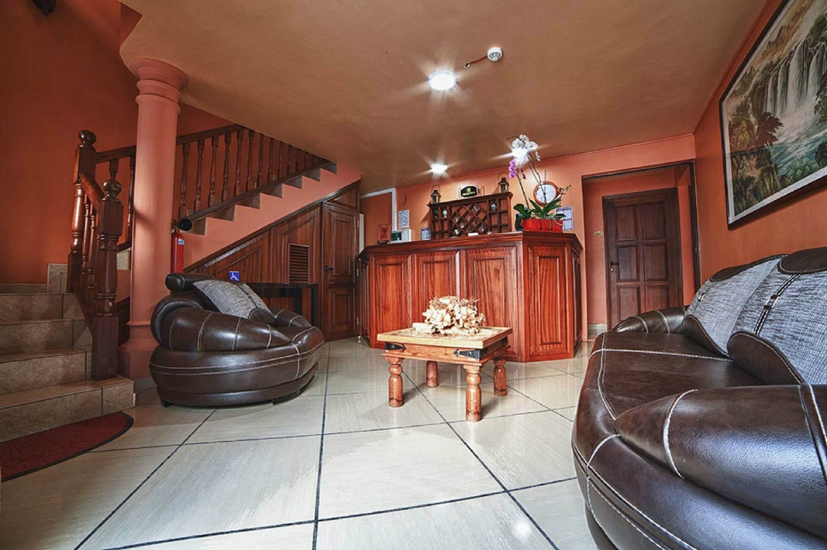 A living room with a staircase, leather sofas, a wooden coffee table, and a fireplace.