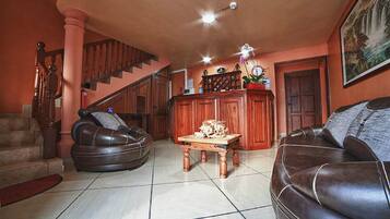A living room with a staircase, leather sofas, a wooden coffee table, and a fireplace.