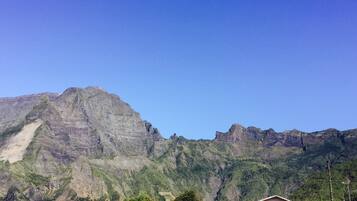 A mountain landscape with a clear sky. There are houses in the foreground with visible roofs and walls.
