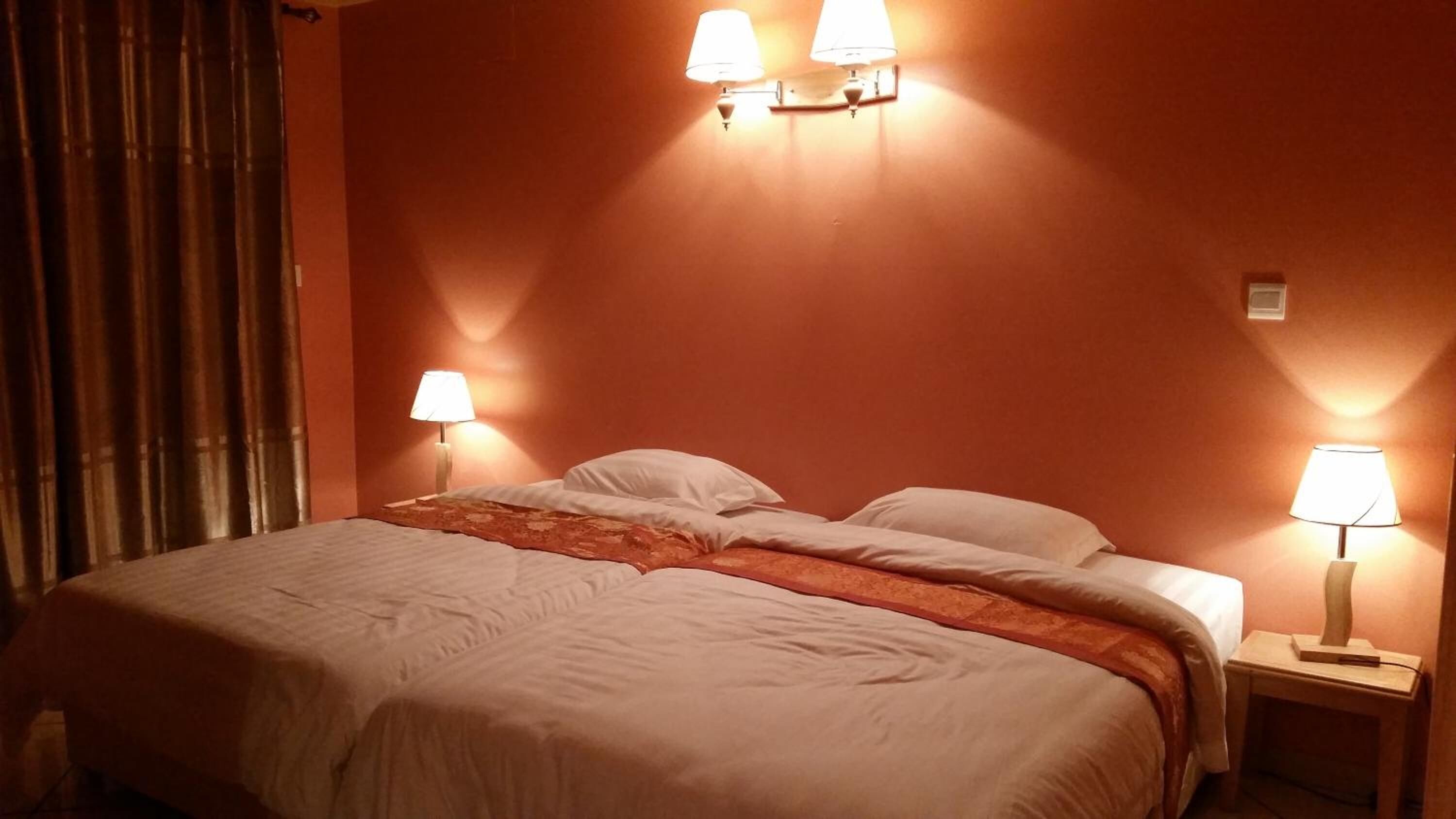 Ein Hotelzimmer mit einem Bett, zwei Nachttischlampen und einem Vorhang.