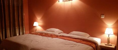 Ein Hotelzimmer mit einem Bett, zwei Nachttischlampen und einem Vorhang.